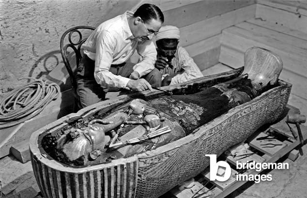 Discovery of the tomb of pharaoh Tutankhamun in the Valley of the Kings (Egypt) - Howard Carter looking into the third coffin of Tutankhamun, 1923 (bw photo), Harry Burton, (1879-1940)  PVDE  Bridgeman Images 